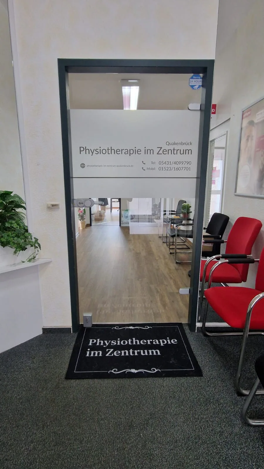 Eingangstür zur Praxis Physiotherapie im Zentrum mit Türschild und Wartebereich.