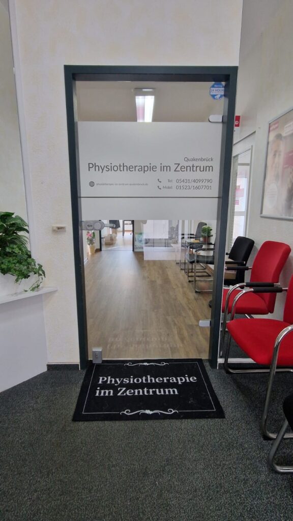 Eingangstür zur Praxis Physiotherapie im Zentrum mit Türschild und Wartebereich.